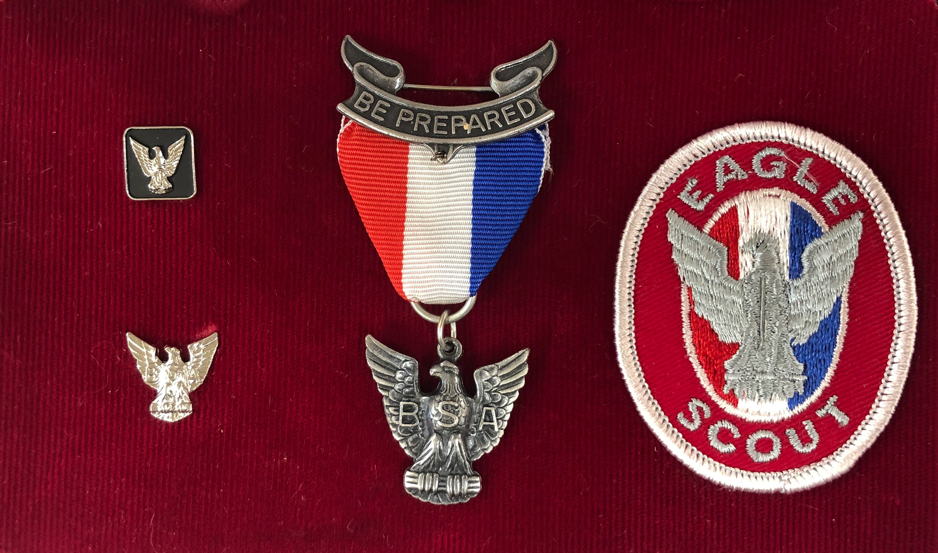 Included in this kit: Eagle tie tack, Mother's pin, Eagle award medal, and Eagle badge. The badge is worn on the left shirt pocket. There are seven ranks achievable by Scouts: Scout, Tenderfoot, Second Class, First Class, Star, Life, and Eagle. With Eagle being the highest attainable rank. In order to attain the rank of Eagle a Scout must earn a minimum of 21 merit badges, 13 of which are required by all Scouts. Since 1969, a silver border outlines the required 13 badges to distinguish them from the rest.